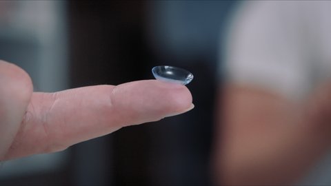 Transparent contact lens in the hands of a man who is preparing to insert it in her eyes