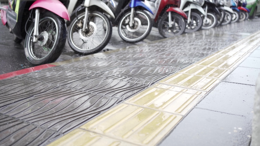 Rain drop on street. Water splashes on roadway. Motorbike parked on the sidewalk.