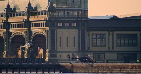 Brooklyn, New York United States - December 3,  2021: Telephoto shot across NY harbor of helicopter landing at heliport in front of Governors Island Ferry Terminal in downtown manhattan.