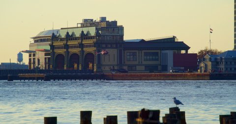 Brooklyn, New York United States - December 3,  2021: Wide shot across NY harbor of helicopter landing at heliport in front of Governors Island Ferry Terminal in downtown manhattan.