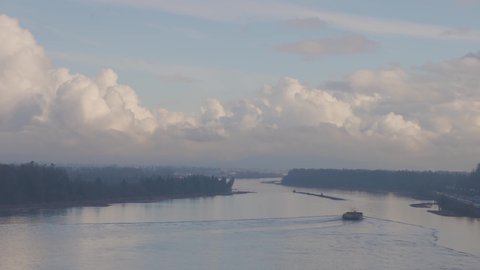 Aerial View of Tugboat in Fraser River and Mountain Landscape in background. Sunny Fall Season Day. Taken on Port Mann Bridge in Surrey, Vancouver, British Columbia, Canada.