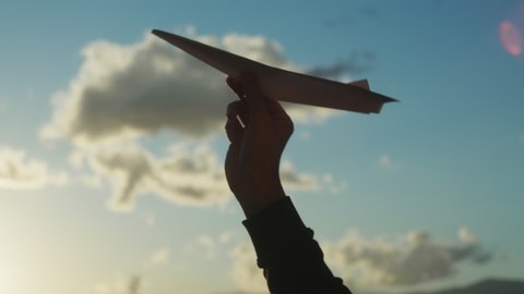 Silhouette of hand with Paper Airplane at sunset