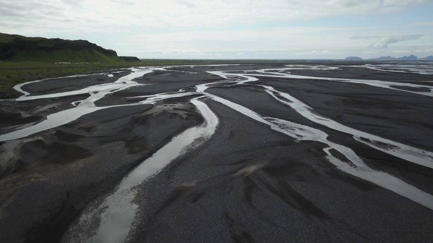 Black sand with streams running through it aerial