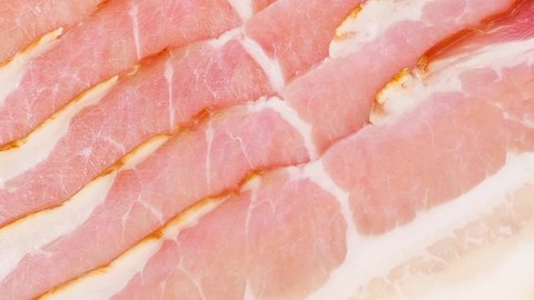 Bacon pork sliced with lard, rotating, close-up macro, top view.