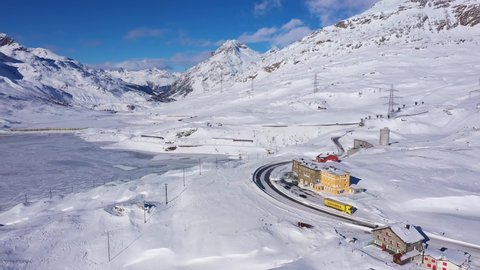 Bernina, Switzerland - December 01 2021: Aerial drone footage of the snow covered Bernina pass road and the white lake in winter in Canton Graubunden in the alps in Switzerland.