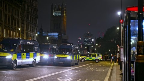LONDON - NOVEMBER 5, 2021: Police vans on Whitehall at night at Million Mask March. Houses of Parliament in the background.