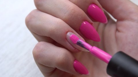 Selfmade manicure service. Manicurist paints nails with pink gel polish. Nail polish application. Manicured pink nails.