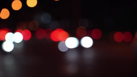 Abstract concept. Round colorful bokeh shine from car lights in traffic jam on city street. Beautiful glittering bokeh in dark blurry background at night. Reflects lonely capital city lifestyle.