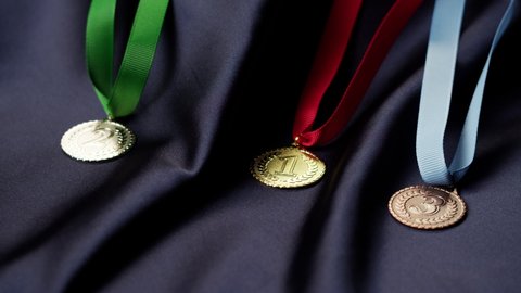Gold, silver and bronze medals with ribbons on black background close-up. First, second and third place. Award and victory, winning the championship. 