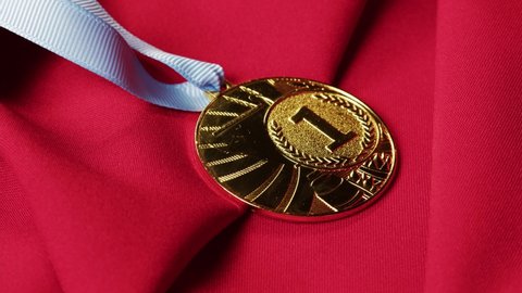 Gold medal with ribbon on red background close-up. The first place. Award and victory, winning the championship. 
