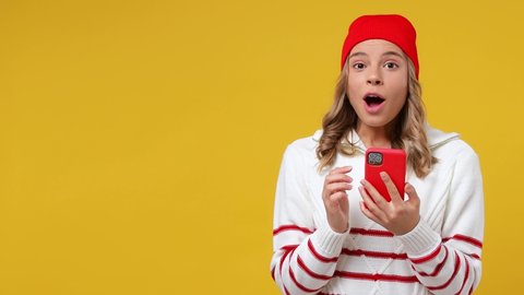 Promoter young girl teen student wears striped shirt hat hold use mobile cell phone look aside on workspace copy space mockup promo commercial area isolated on plain yellow background studio portrait