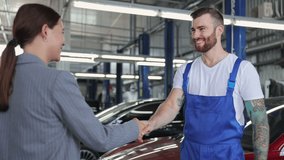 Young brunet mechanic man 20s wears denim overalls white t-shirt work in vehicle repair shop communicate pass car key to business woman customer handshake on light modern workshop background indoors - Powered by Shutterstock - Get 15% off with code: PIKWIZARD15