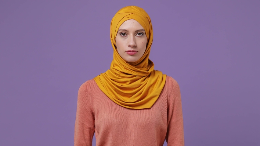 Displeased irritated young arabian asian muslim woman in abaya hijab yellow clothes closed eyes cover ears do not want to listen scream isolated on plain pastel light violet background studio portrait Royalty-Free Stock Footage #1083702469