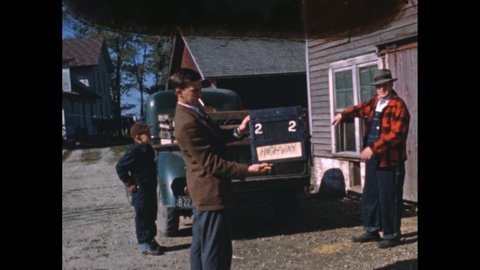 1950s: Man and boy load crates of turkeys into back of pickup truck.