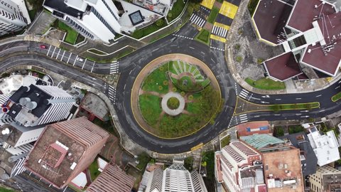 Aerial view of paved street in a circle with nature in the center, traffic and lifestyle in a city with buildings, Latin America in Quito Ecuador, architecture