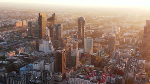 Slide and pan aerial panoramic footage of modern downtown buildings in morning sun glow. Warsaw, Poland