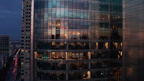 Rising footage of modern futuristic high rise office building with glossy glass facade reflecting sunset sky. Warsaw, Poland