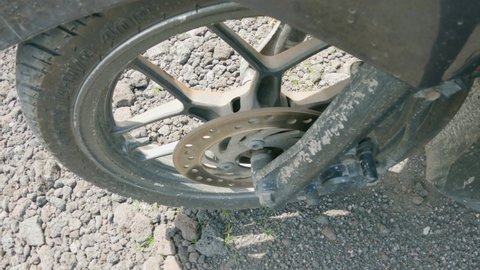 Close-up of motorcycle wheel driving along stone road on sunny summer day. Detail of motorbike while driving off-road. Interesting view angle. Operation of suspension shock absorbers and brakes