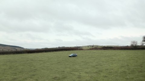 Cinematic follow drone shot of farmer driving 4x4 around an empty field