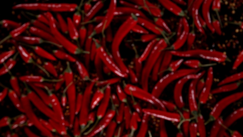 Super slow motion of flying red hot chilli peppers isolated on black background. Overhead view, filmed on high speed cinema camera, 1000 fps. Ultimate perspective of flying food. Speed ramp effect. Royalty-Free Stock Footage #1083716641