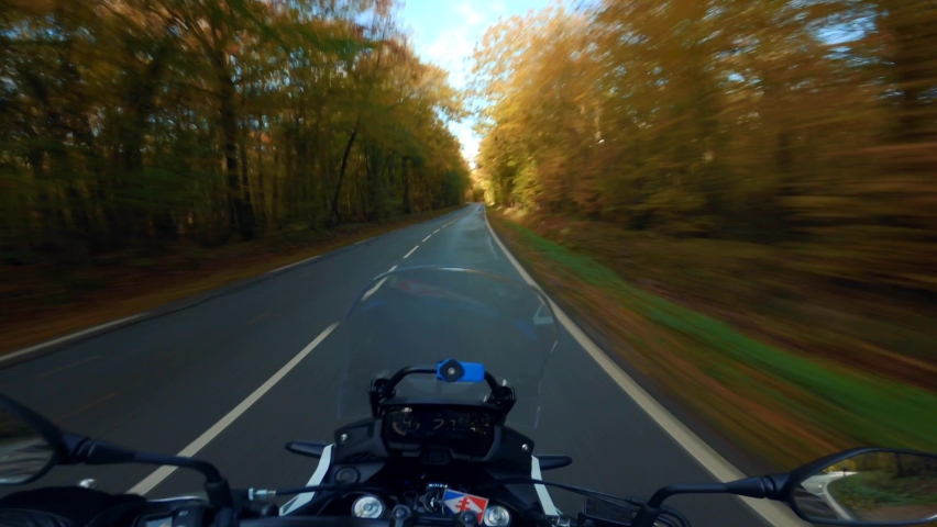 A scenic motorcycle ride at fall, in the French forest of Rambouillet in October, on a beautiful golden road