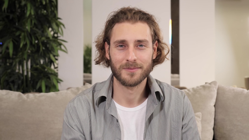 Happy cheerful handsome man showing two thumb up sign sitting on sofa at home, male looking at camera smiling when showing thumb up, Positive human face and gesturing expression, head shot.