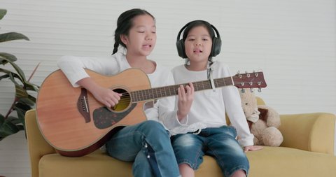 Two sisters are having a fantastic time in the living room. From the comfort of your own home, you may play guitar and sing a song together.