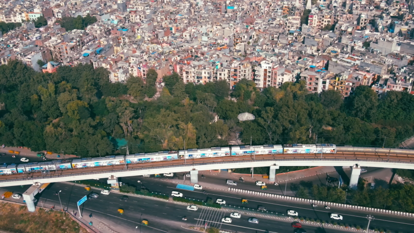 Aerial view of Indian capital and metropolitan city of New Delhi, India. Drone shot of metro rail moving above 8 lane highway and flyover bridges in Delhi. Roads of developing India. Indian Cityscape  | Shutterstock HD Video #1083722128