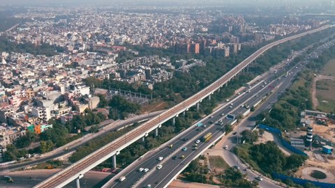 Aerial view of Indian capital and metropolitan city of New Delhi, India. Drone shot of 8 lane highway in Delhi. Roads of developed India. Metro rail track with highways and cityscape, India. 4K