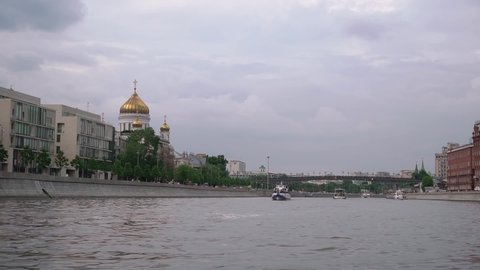 Sailing on a ship on the Moskva River. Summer day in Moscow, Russia. Cathedral of Christ the Savior, tourist yachts and boats, city embankments. The bridge and the domes of the Kremlin.