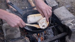 Cooking Meat Shawarma Wrapped in Pita on Outdoor, Burning Bonfire, in Pan. Tourist fries juicy, crispy lavash in blazing, smoking flame, fire. Concept of food, hiking, survival in nature, in wood. 4K.