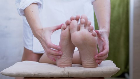 Female Hands are Massaging Bare Legs, Feet, Soles of a Child. Pressing acupuncture points of foot with fingers. Prevention of pain in heel, relaxation of muscles, improvement of blood circulation. 4K.