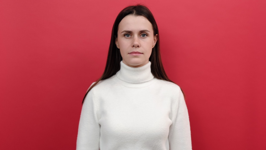 Yes sir! Portrait of responsible patriotic young woman in white sweater following discipline, saluting to commander with hand near temple and listening order, isolated on red color background studio