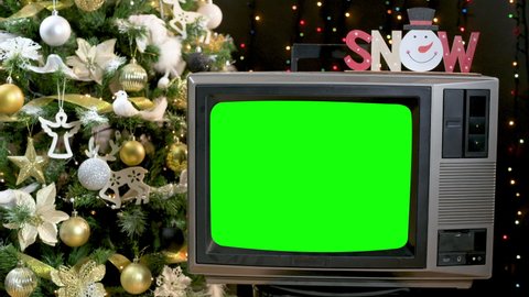 Woman hand turn on Vintage old tv with green screen and changing canals in front of Christmas tree