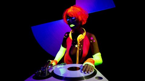 A cool sexy djing woman wearing UV fluorescent clothing and makeup