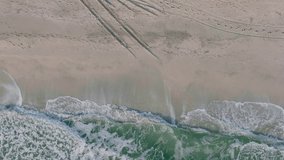 aerial view with waves crashing on sandy shore