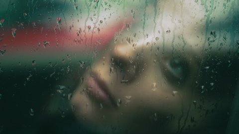 solitude, sadness - depressive woman behind the glass wet with rain