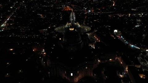 Aerial drone night flyover video of Saint Peter's square, world's largest church - Papal Basilica of St. Peter's, Vatican - an elliptical esplanade created in the mid seventeenth century, Rome, Italy