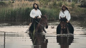 Happy women friends in loose white shirts ride horses wading across river with reeds while dog swims following on summer day - Powered by Shutterstock - Get 15% off with code: PIKWIZARD15