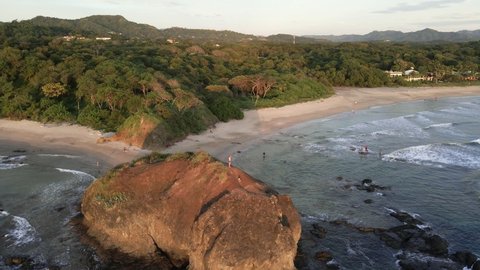 Father and son standing on a large beach rock at playa Grande near Tamarindo, Costa Rica. Still aerial footage in 4k of a stunning beach sunset.
