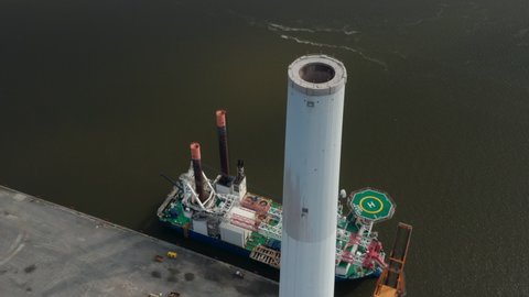 Aerial view of the chimney of Esbjerg Power Station in Denmark. Drone view revealing Liebherr Seafox 5, the biggest offshore crane moored at harbour