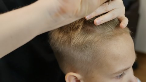 the barber's hands grab the hair between the fingers and cut with scissors and a lilac comb. trendy teen haircut in slow motion