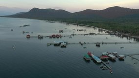 aerial drone shot of floating fishing village in Phu Quoc island, Vietnam. Dusk time, after sunset, calm sea water in the bay, houses on water, piers. 