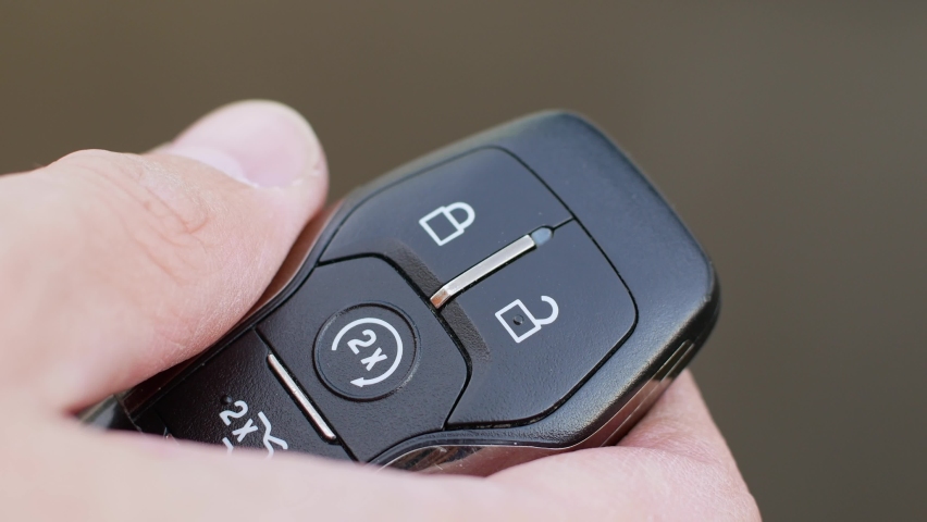 Man locks and unlocks car with key fob close-up on light gray background - Powered by Shutterstock - Get 15% off with code: PIKWIZARD15