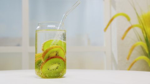 Detox drink made from fresh kiwi in sparkling water in glass jar with straw on light background. Mojito fruit cocktail.