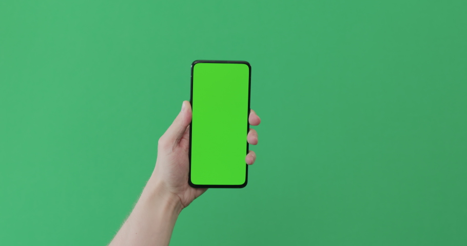 Young man hand touch smartphone with green screen on green background | Shutterstock HD Video #1083753025