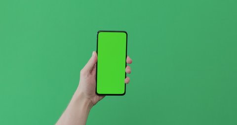 Young man hand touch smartphone with green screen on green background Adlı Stok Video