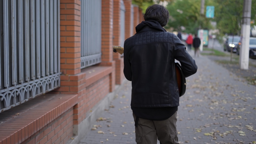 Man walking down the street and playing on the guitar