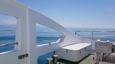 4k video, view from the deck of a luxury yacht to the sea and the horizon line on the background of the sea, bright sunlight, boat movement on the waves