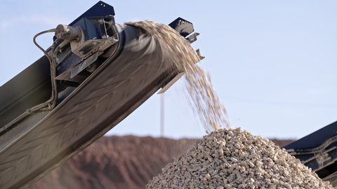 Mobile portable crushing screening plant. Mining conveyor belt sorts rock and loading stones in truck. Heavy machinery working for minerals extraction. Mining extractive industry.